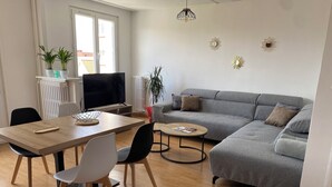 A modern living room with a grey sofa, a wooden dining table, and a TV. - Chez Julien,lumineux-accueillant-spasieux (Troyes)