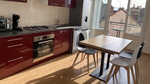 A modern kitchen with a dining area, a gas stove, a coffee maker, and a refrigerator. - Chez Julien,lumineux-accueillant-spasieux (Troyes)
