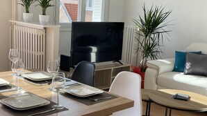 A modern living room with a dining area, a flat-screen TV, and potted plants. - Chez Julien,lumineux-accueillant-spasieux (Troyes)