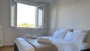 A bedroom with a bed, white bedding, a window, and a radiator. - Chez Julien,lumineux-accueillant-spasieux (Troyes)