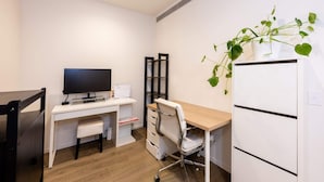 A small, modern office space with a white desk, a computer, a television, a chair, and a refrigerator. - Stunning 1-bed Unit in 56th Floor in Southbank! (Southbank)