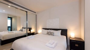 A modern hotel room with a large bed, a bedside table with a lamp, a mirror, and a wall-mounted artwork. - Stunning 1-bed Unit in 56th Floor in Southbank! (Southbank)