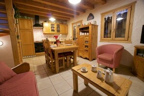 A cozy living room with a wooden dining table, a pink armchair, and a sofa. - Chalet, view village/ski slopes, sauna, terrace, parking, ski locker, 70m², Les Gets (Les Gets)