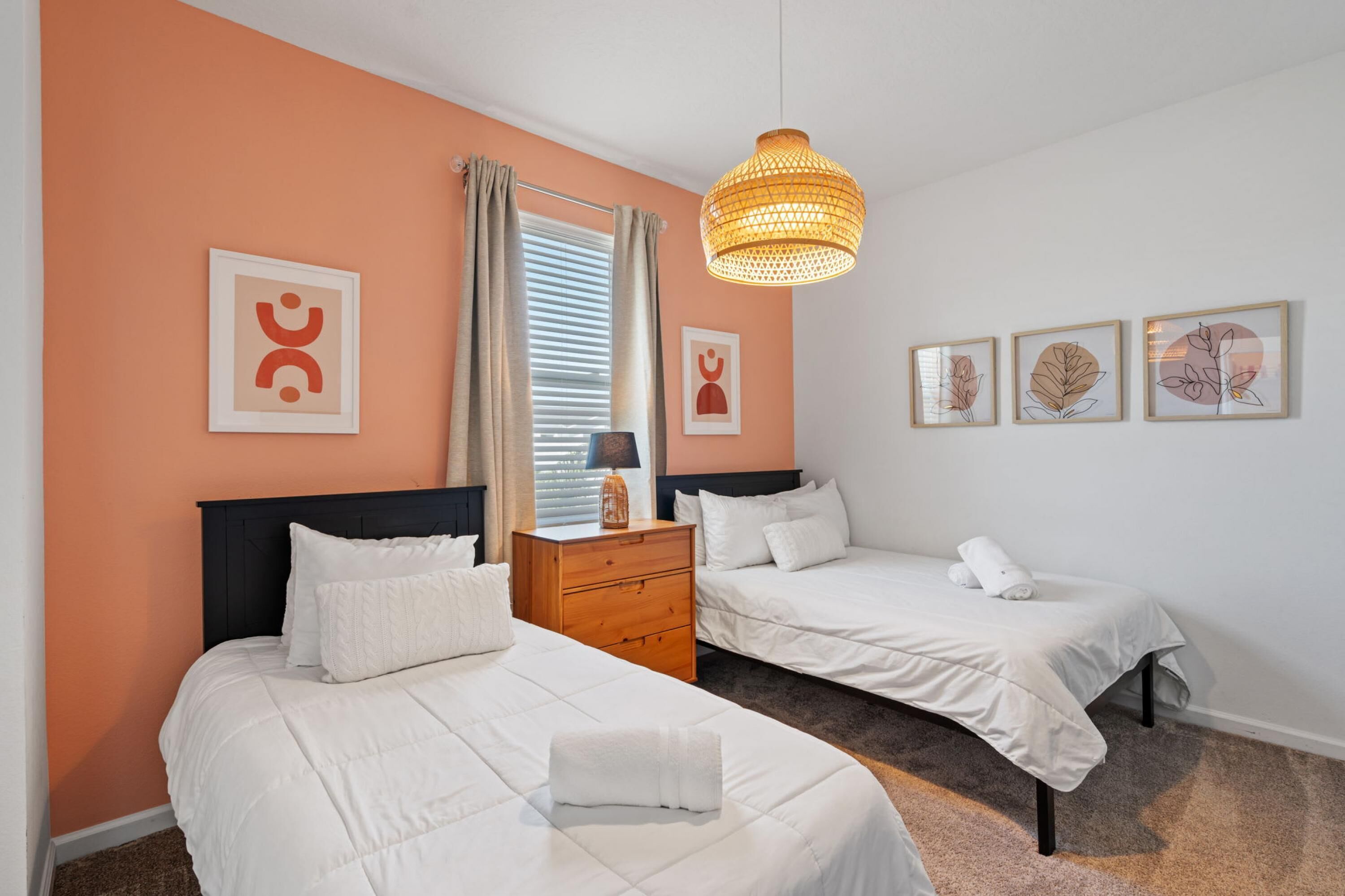 Una habitación de hotel con dos camas, un aparador de madera, un escritorio y una lámpara colgante.