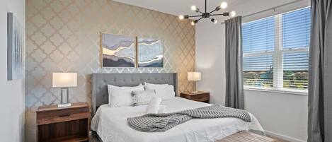 A bedroom with a bed, bedside tables, a bench, a ceiling light, and a window with curtains.