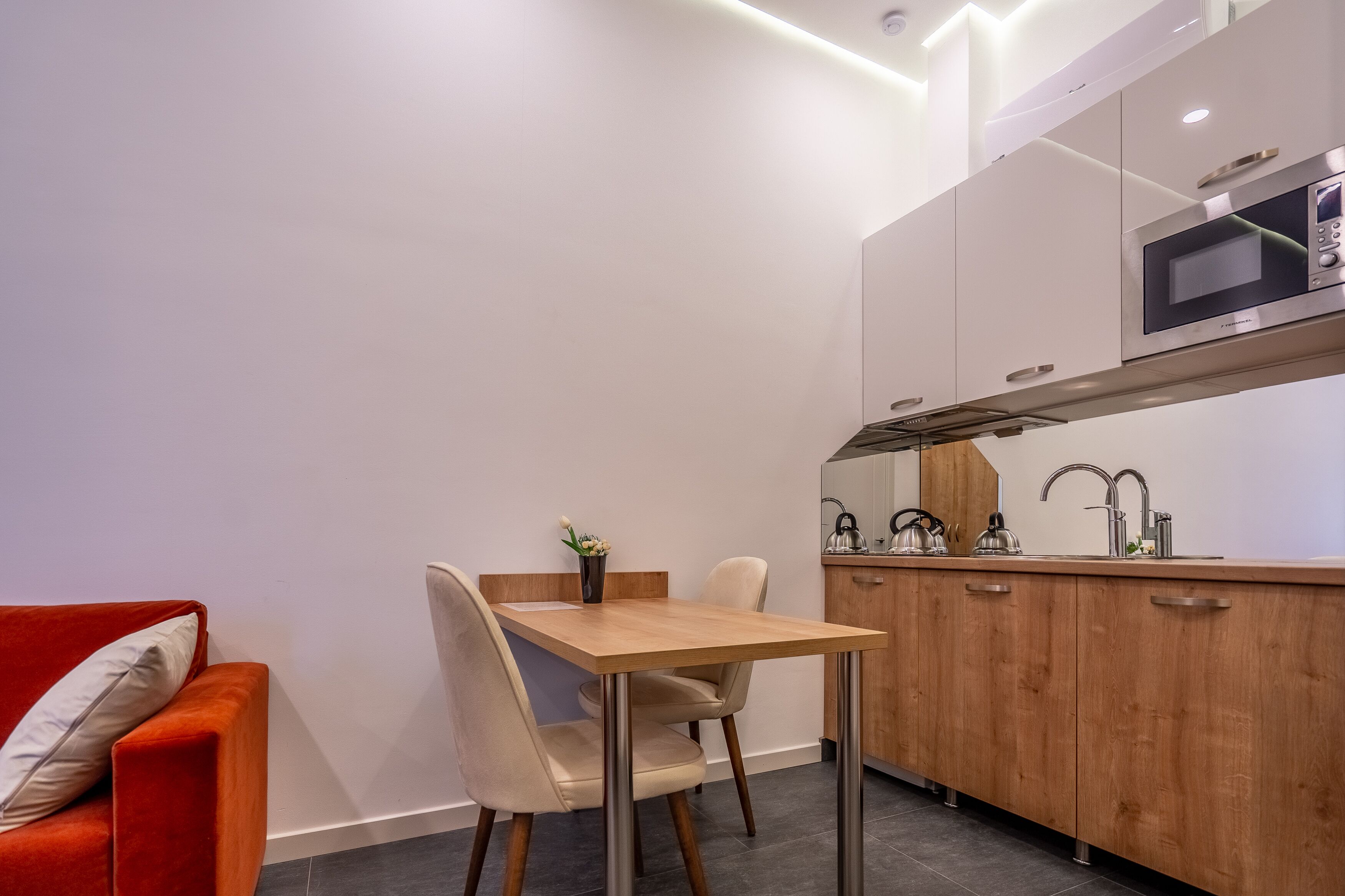 A compact kitchen with a wooden table and chairs, a microwave, and a sink.