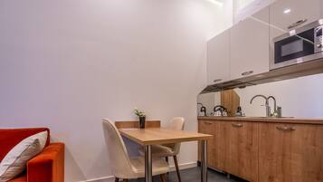 A compact kitchen with a wooden table and chairs, a microwave, and a sink.