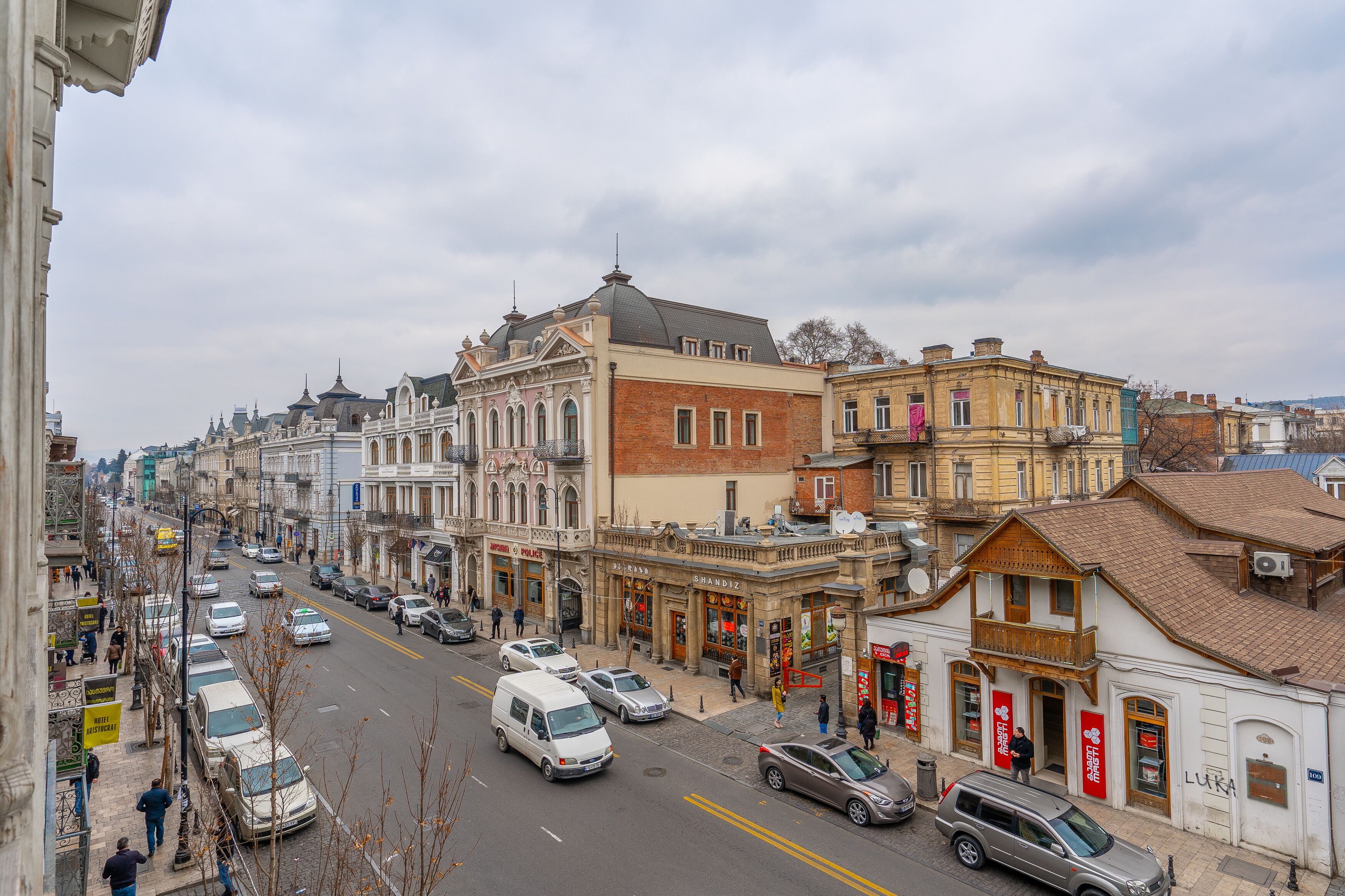 A street view with buildings, cars, and pedestrians.