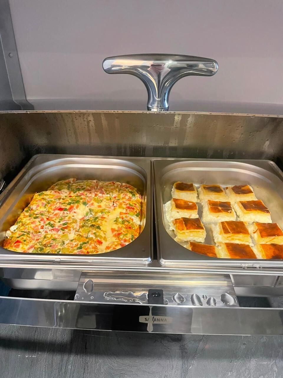 Un buffet composé de deux plateaux : l’un contient un plat en cocotte et l’autre, des petits pains.