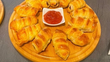 Een ronde houten plank met goudbruine gebakjes en een kleine schaaltje rode saus.