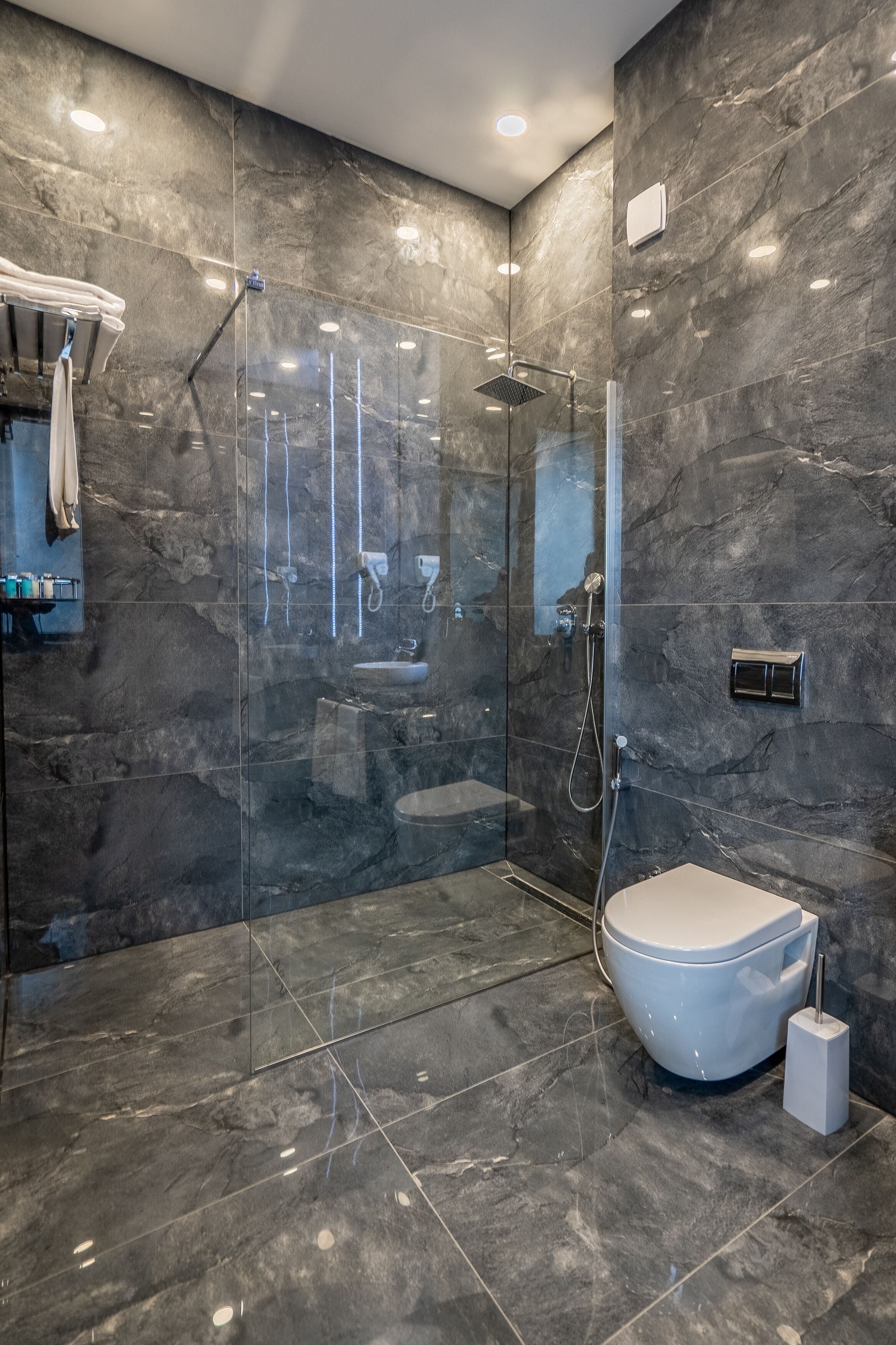 A modern bathroom with a glass-enclosed shower, a white toilet, and a marble floor.