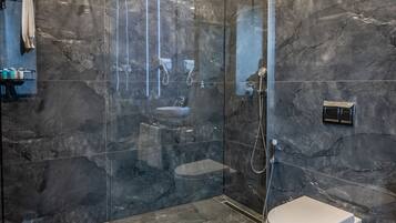 A modern bathroom with a glass-enclosed shower, a white toilet, and a marble floor.
