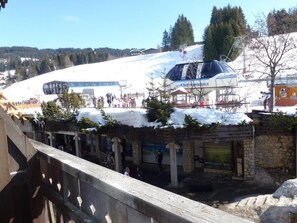 Une station de ski dotée d’un grand télésiège et d’un petit bâtiment à la façade en pierre.