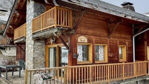 Eine Holzhütte mit Steinverzierungen, einem Balkon und einem Steinkamin.