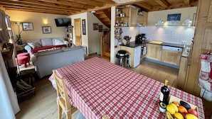 Ein gemütliches Zimmer mit einem karierten Tisch, einer Couch, einer kleinen Küche und einer Treppe.