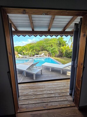 Une terrasse en bois avec une piscine et des chaises longues.