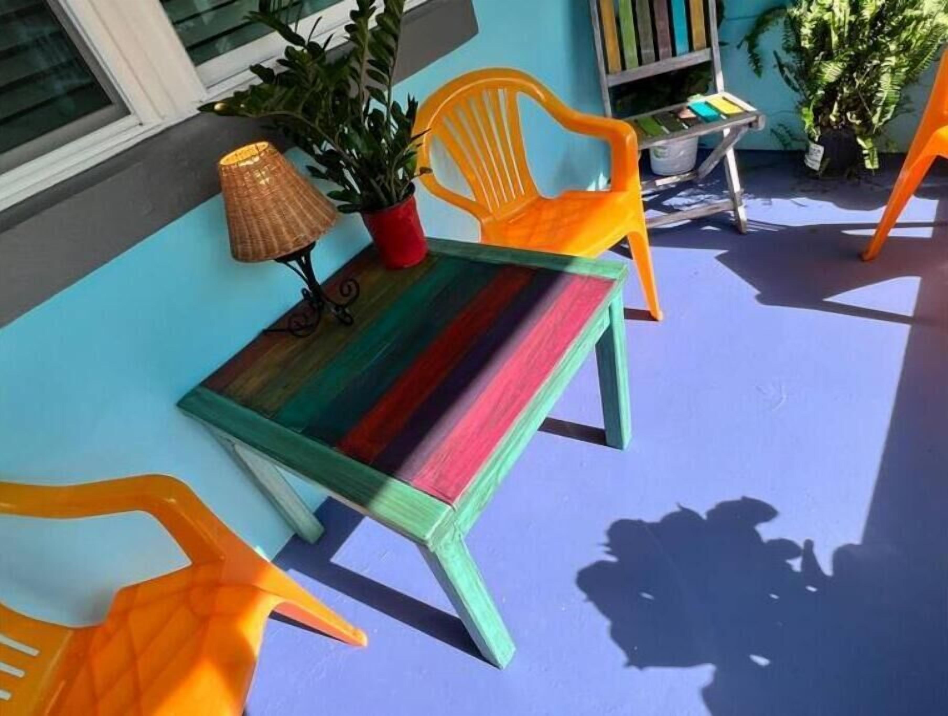 A colorful outdoor seating area with a table and chairs, a potted plant, and a lamp.