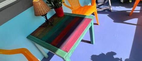 A colorful outdoor seating area with a table and chairs, a potted plant, and a lamp.