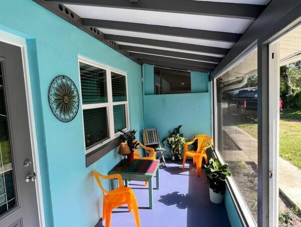 A covered outdoor area with a table and chairs, a decorative wall piece, and potted plants. - 875 Oasis #1. Location!

 (Vero Beach)