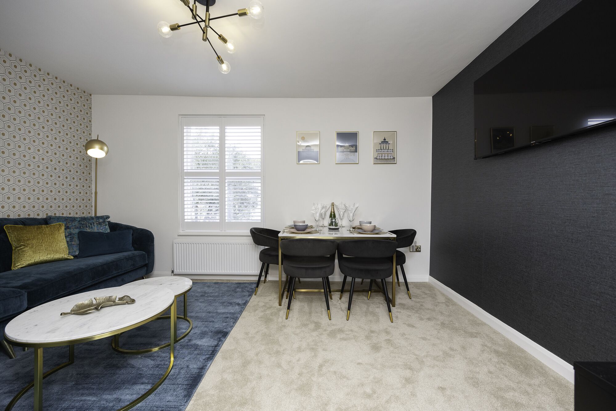 Een moderne woonkamer met een donkerblauwe bank, een witte salontafel, en een eethoek met een witte tafel en zwarte stoelen.