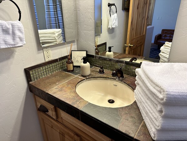 A bathroom with a sink, mirror, towel rack, and a decorative bottle.