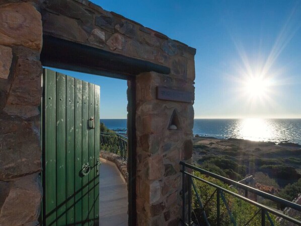 A stone archway leading to a balcony with a view of the ocean.