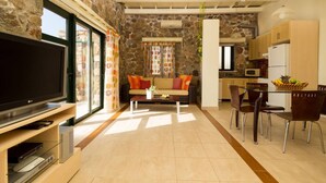 A living room with a TV, sofa, and dining area with chairs. - Seaview villa w/private pool near Elafonissi beach (Chania)