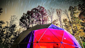 A geodesic dome tent with a starry night sky in the background.
