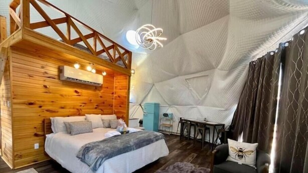A cozy bedroom with a wooden headboard, a bed with pillows, a small rug, and a fluffy rug on the floor.