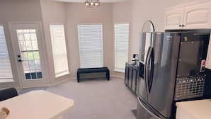 A modern kitchen with a stainless steel refrigerator, white cabinetry, and a bench. - 4 bedrooms+Outdoor gazebo+Garage+office (Tulsa)