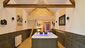 A modern bathroom with a central hot tub, wooden beams, and a staircase leading to an upper level. - Inédit! Spa, Piscine, Salle de Jeux (La Poterie-Cap-d'Antifer)