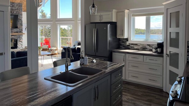Una cucina moderna con una grande isola, elettrodomestici integrati e vista sull'esterno.