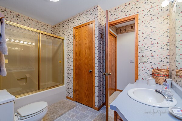 Un baño con ducha, inodoro, lavamanos y espejo.