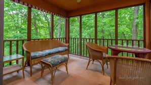 A covered porch with wicker furniture, a ceiling fan, and large windows overlooking a forest. - House 3bd-3bth-fire pit-screen porch-outdoor pool - close to everything (Galena)