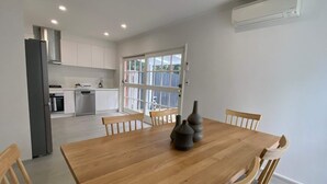 Una cocina moderna con armarios blancos, una mesa de comedor de madera y un amplio ventanal.