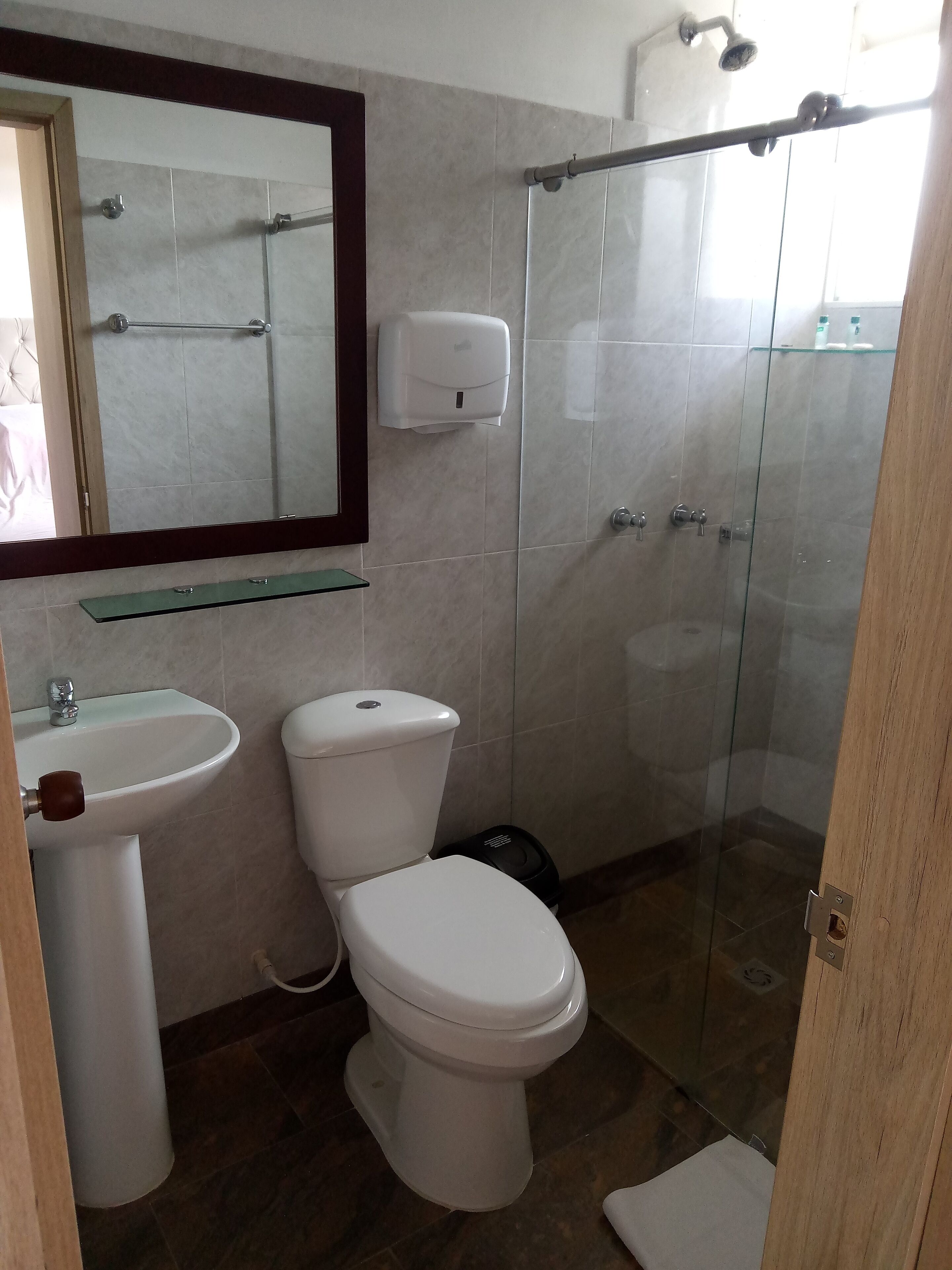 A bathroom with a toilet, sink, and glass shower enclosure.