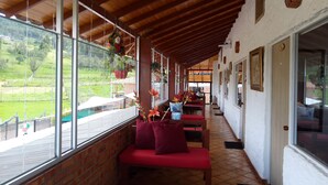 Un’area salotto all’aperto riparata, con pareti in mattoni, ampie finestre e piante pensili.