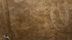 A bathroom with a bathtub, tiled walls, and a yellow accent wall. - American Inn (Sumter)