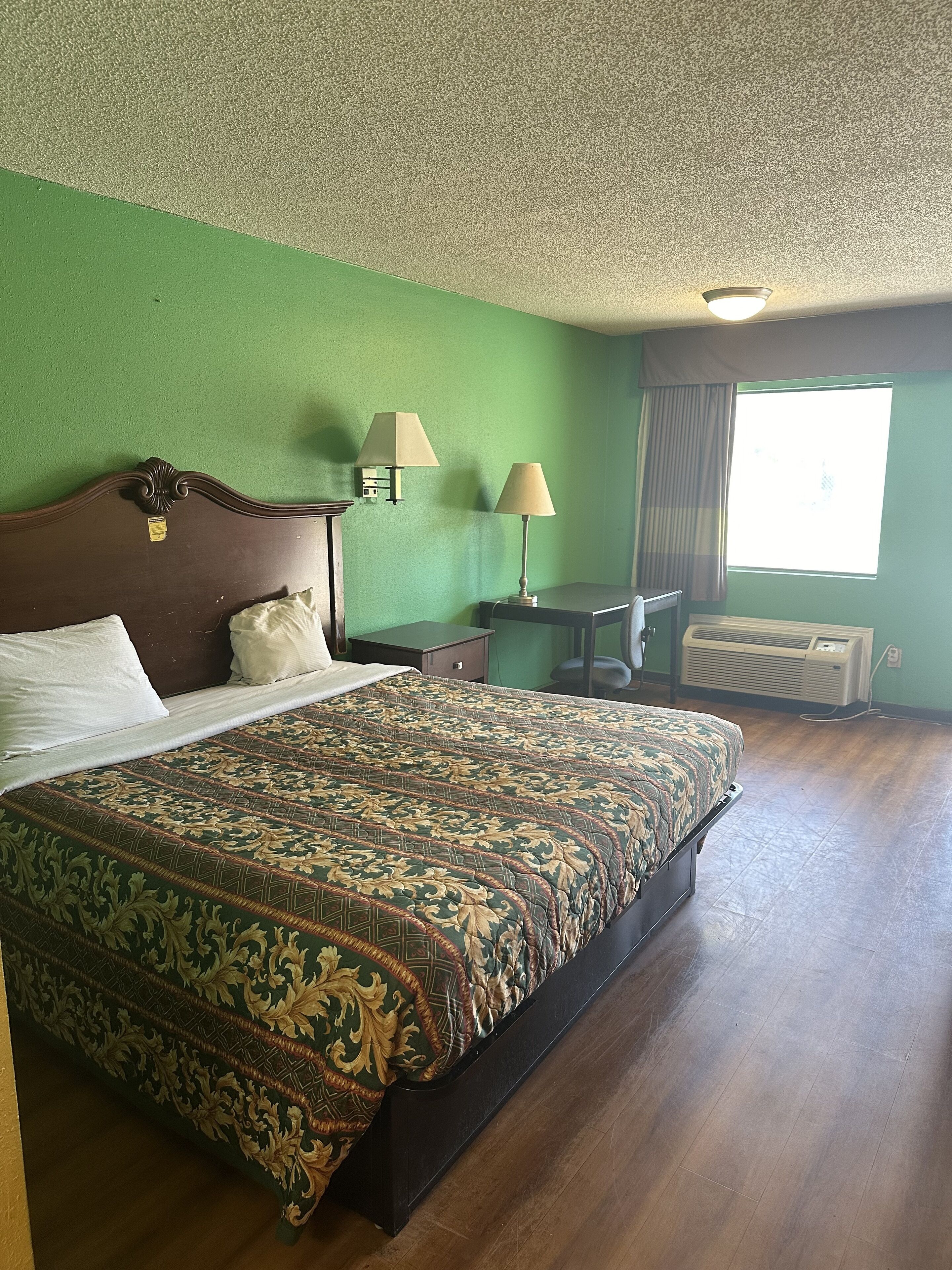Habitación de hotel con una cama grande, dos lámparas de noche, un escritorio y una ventana con cortinas.