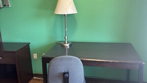 A desk with a lamp, a chair, and a green wall. - American Inn (Sumter)