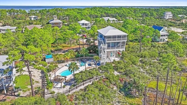 Une propriété située sur la côte, avec une grande maison dotée d’un balcon imposant, d’une piscine et d’une vue sur l’océan.