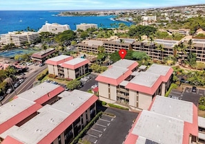 A hotel complex with multiple buildings, a parking area, and a view of the ocean.