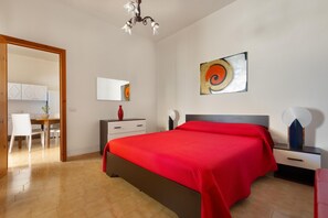 Cozy retreat with a large bed, modern chandelier, and a desk for work or study.