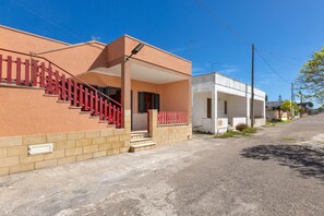 Stylish two-story residence with a red metal staircase and a covered entrance area.