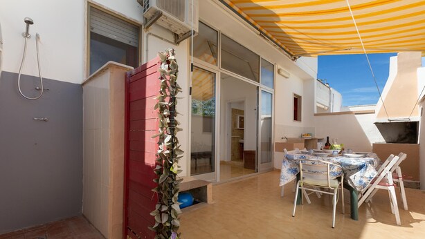 A covered patio area with a table and chairs, a red cabinet, and a shower.