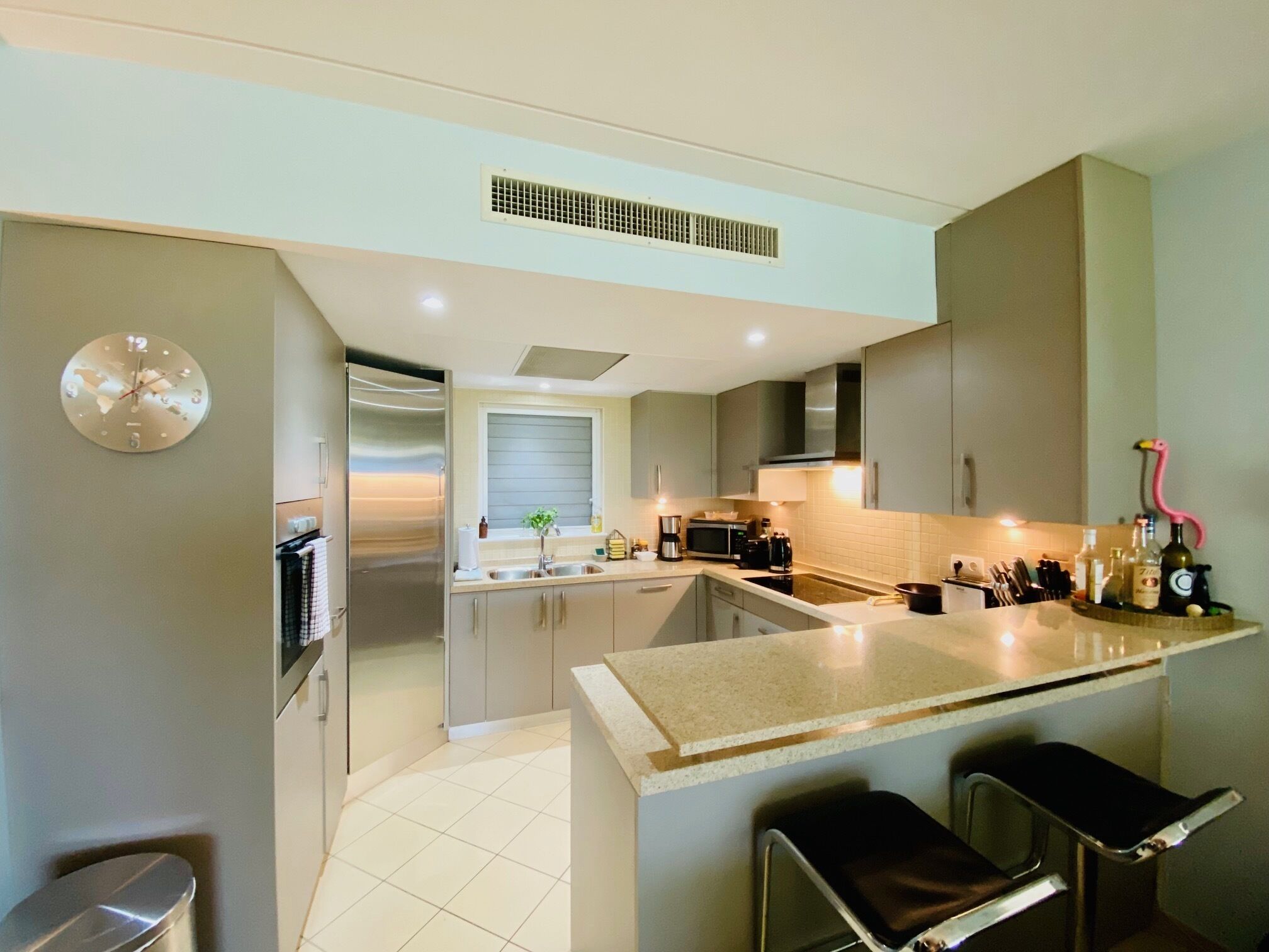 A modern kitchen with a central island, stainless steel appliances, and a visible window.