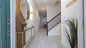 A hallway with a wooden console table, a mirror, and a staircase. - Beautiful & Cozy Home at Storey Lake Resort (Kissimmee)