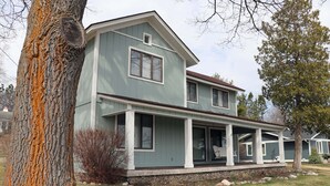 A two-story house with a porch and a stone foundation.