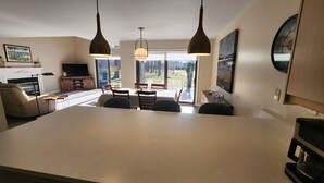 Eine moderne Küche mit einer zentralen Kochinsel, Pendelleuchten und Blick ins Freie.