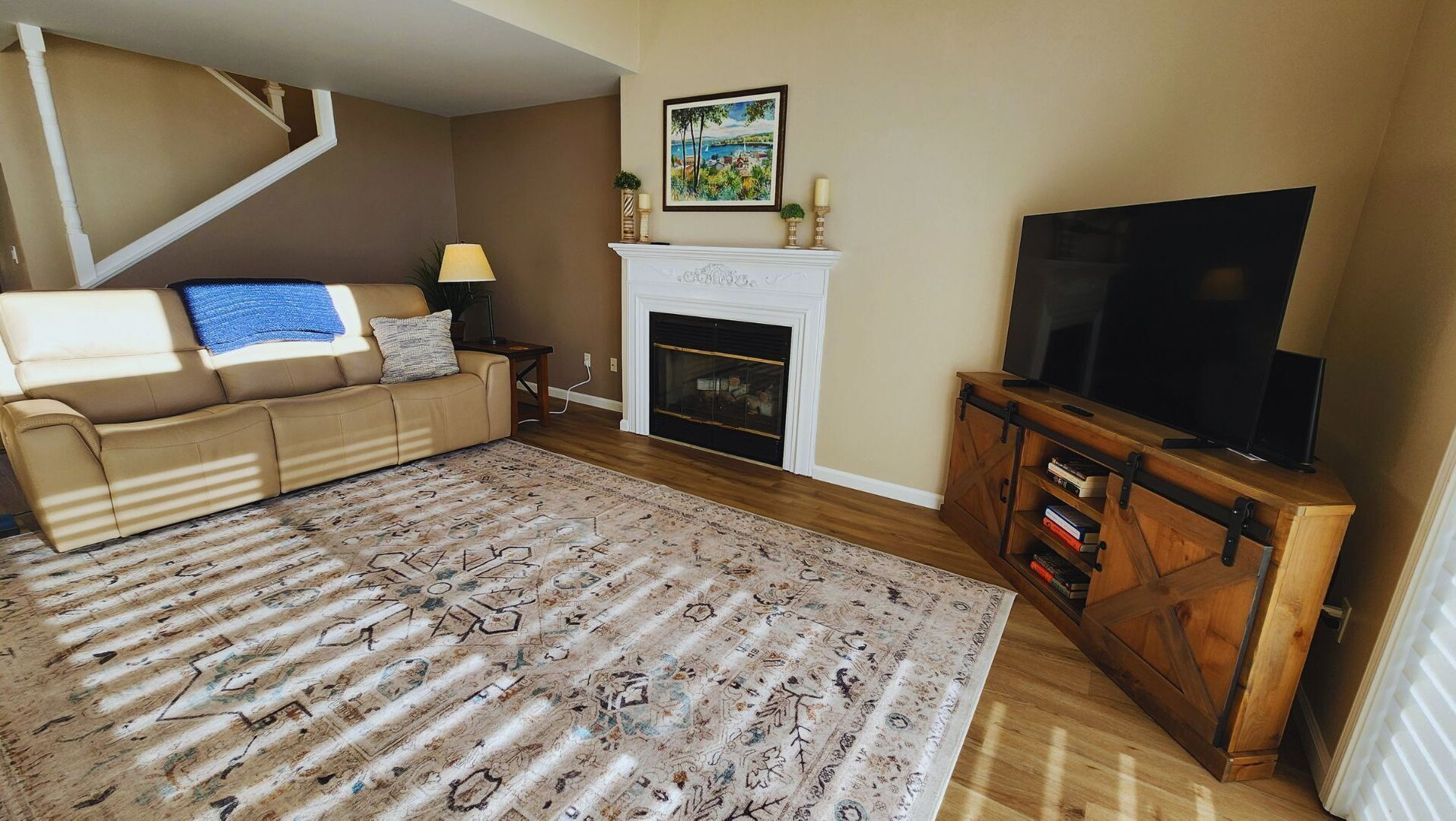 A living room with a sofa, a fireplace, a television, and a patterned rug.